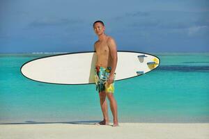 hombre con tabla de surf en la playa foto