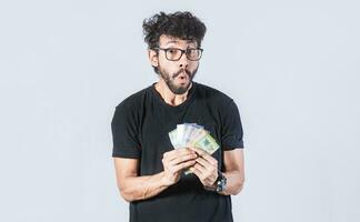 Amazed man with money in hand, man in glasses amazed with banknotes in hand, concept of man earning money photo