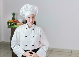 Portrait of a female nutritionist in uniform with fresh vegetables on the table, A female nutritionist with a table of vegetables, Portrait of a female chef surrounded by fresh vegetables photo