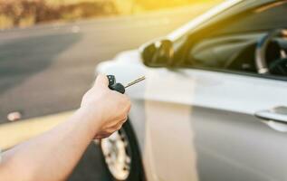 Close-up of driver outside car holding keys. Driver hands showing the car keys, Driver hands showing the keys outside the vehicle, Vehicle rental concept photo