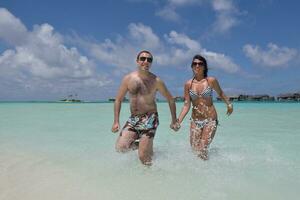 feliz pareja joven divertirse en la playa foto