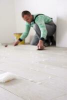 worker installing the ceramic wood effect tiles on the floor photo