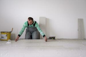 worker installing the ceramic wood effect tiles on the floor photo