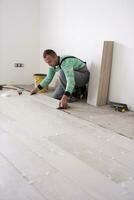 worker installing the ceramic wood effect tiles on the floor photo