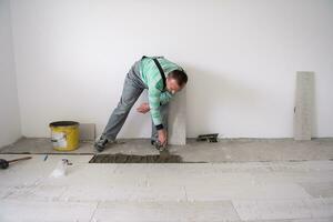 worker installing the ceramic wood effect tiles on the floor photo