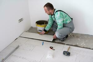 worker installing the ceramic wood effect tiles on the floor photo