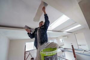 construction worker plastering on gypsum ceiling photo