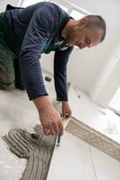 worker installing the ceramic wood effect tiles on the floor photo