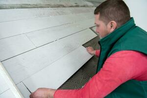 worker installing the ceramic wood effect tiles on the floor photo