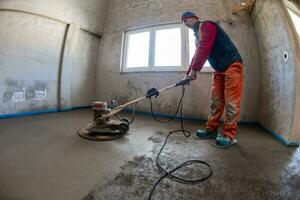 trabajador realizando y puliendo suelo de solera de cemento y arena foto