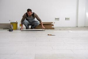 worker installing the ceramic wood effect tiles on the floor photo