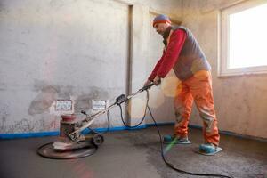trabajador realizando y puliendo suelo de solera de cemento y arena foto