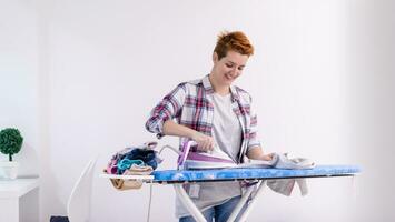 mujer pelirroja planchando ropa en casa foto