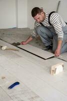 worker installing the ceramic wood effect tiles on the floor photo