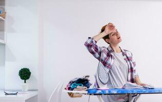 Red haired woman ironing clothes at home photo