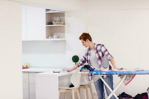 mujer pelirroja planchando ropa en casa foto
