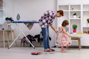 mother helping daughter while putting on a dress photo