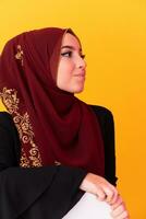 beautiful muslim woman in fashinable dress with hijab isolated on modern yellow background representing concept of modern islam and ramadan kareem photo