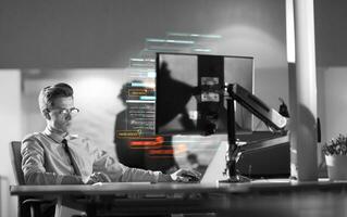 man working on computer in dark office photo