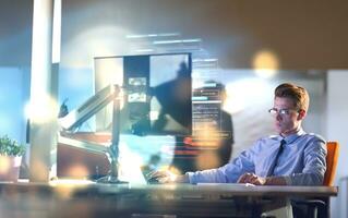 man working on computer in dark office photo