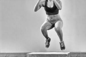 black woman is performing box jumps at gym photo