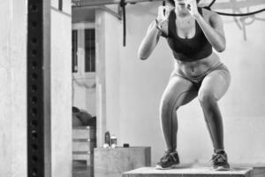 black woman is performing box jumps at gym photo