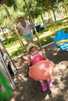 mother and daughter swinging in the park photo