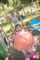 mother and daughter swinging in the park photo