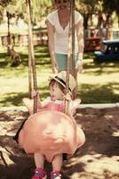 mother and daughter swinging in the park photo