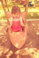 little girl swinging  on a playground photo