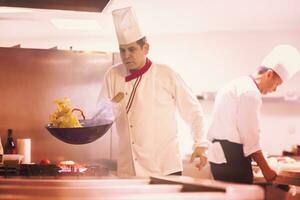 chef volteando verduras en wok foto