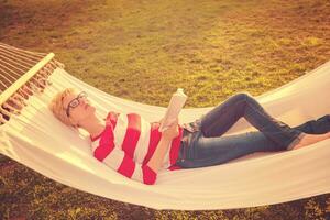 woman reading a book while relaxing on hammock photo