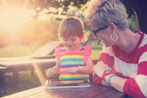 mom and her little daughter using tablet computer photo