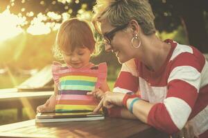 mom and her little daughter using tablet computer photo