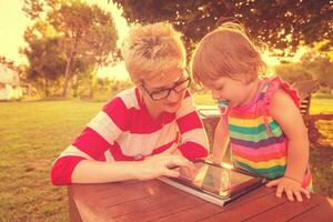 mom and her little daughter using tablet computer photo