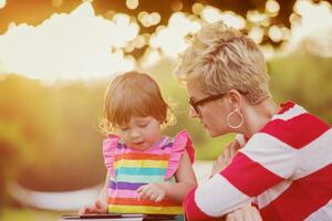 mom and her little daughter using tablet computer photo