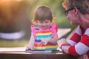 mom and her little daughter using tablet computer photo