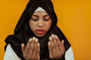 African muslim woman wearing hijab and traditional muslim clothes posing in front of yellow background photo
