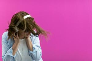 Brunette lady in black glasses dancing and listening music isolate on pink background photo