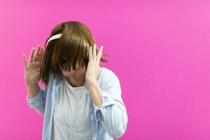 Brunette lady in black glasses dancing and listening music isolate on pink background photo