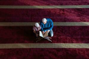 muslim prayer father and son in mosque praying and reading holly book quran together islamic education concept photo