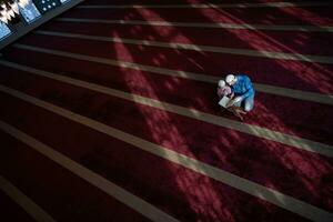 muslim prayer father and son in mosque praying and reading holly book quran together islamic education concept photo