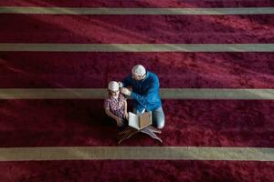 muslim prayer father and son in mosque praying and reading holly book quran together islamic education concept photo