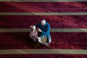 muslim prayer father and son in mosque praying and reading holly book quran together islamic education concept photo