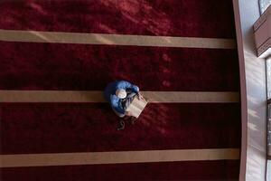 muslim man praying Allah alone inside the mosque and reading islamic holly book photo