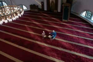 muslim prayer father and son in mosque praying and reading holly book quran together islamic education concept photo