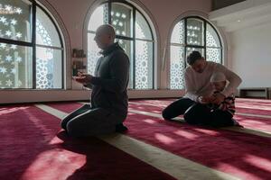 muslim prayer father and son in mosque praying and reading holly book quran together islamic education concept photo