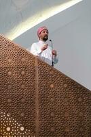 el joven imán árabe musulmán tiene un discurso en la oración del viernes por la tarde en la mezquita. foto