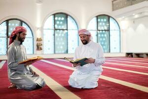 two muslim people in mosque reading quran together concept of islamic education photo
