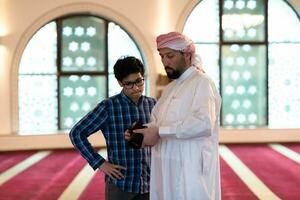 the father explains to his son how to use the camera in mosque photo